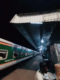 A train station at night, a men selling local food, an intercity train can be seen. 