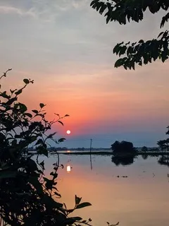 Sunset over floodwater in a field with the sun's reflection on the water